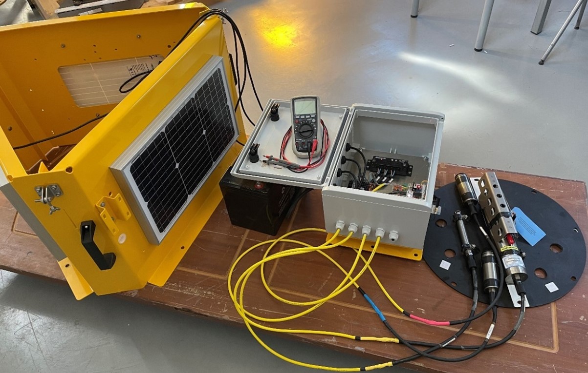 Buoy electronics system with solar panel, battery and wired sensors laid out for testing
