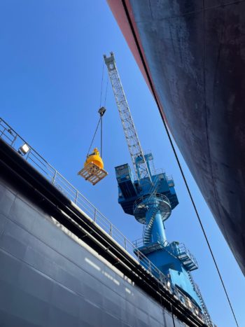 Ship's crane lifting a buoy from the quayside
