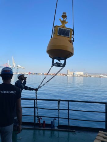 Buoy suspended from a crane over the ship's side